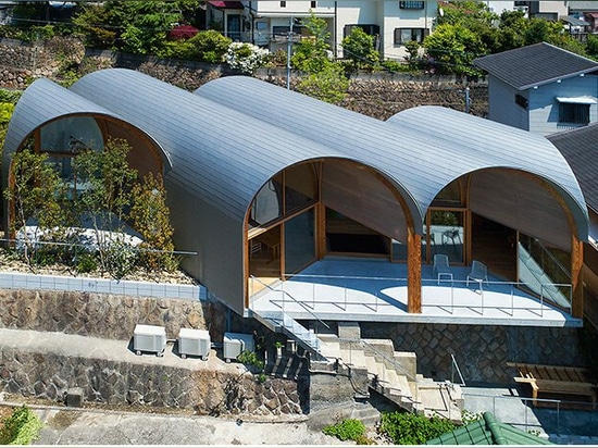 Una serie di tetti a volta inclinati sormonta la casa di legno di tomohiro hata a koyoen, Giappone