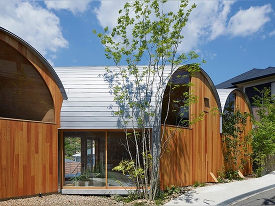 Una serie di tetti a volta inclinati sormonta la casa di legno di tomohiro hata a koyoen, Giappone