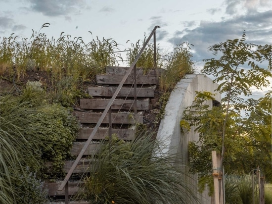 Una casa che si erge dal terreno formando un giardino a tre livelli