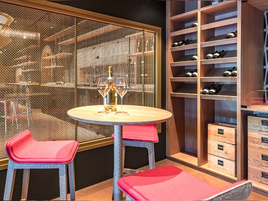 Uno spazio contemporaneo per la degustazione di vini è caratterizzato dalla rete metallica intrecciata in ottone M22-83 come divisorio per la sala di degustazione.