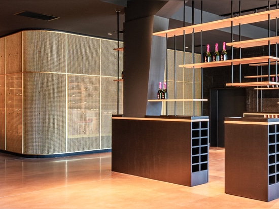 Uno spazio contemporaneo per la degustazione di vini è caratterizzato dalla rete metallica intrecciata in ottone M22-83 come divisorio per la sala di degustazione.